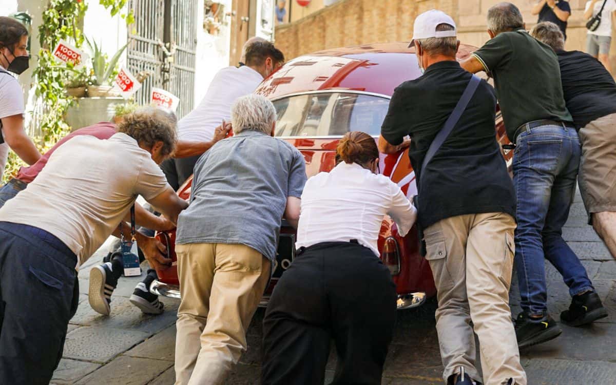Spectators push a car during the 1000 Miglia.