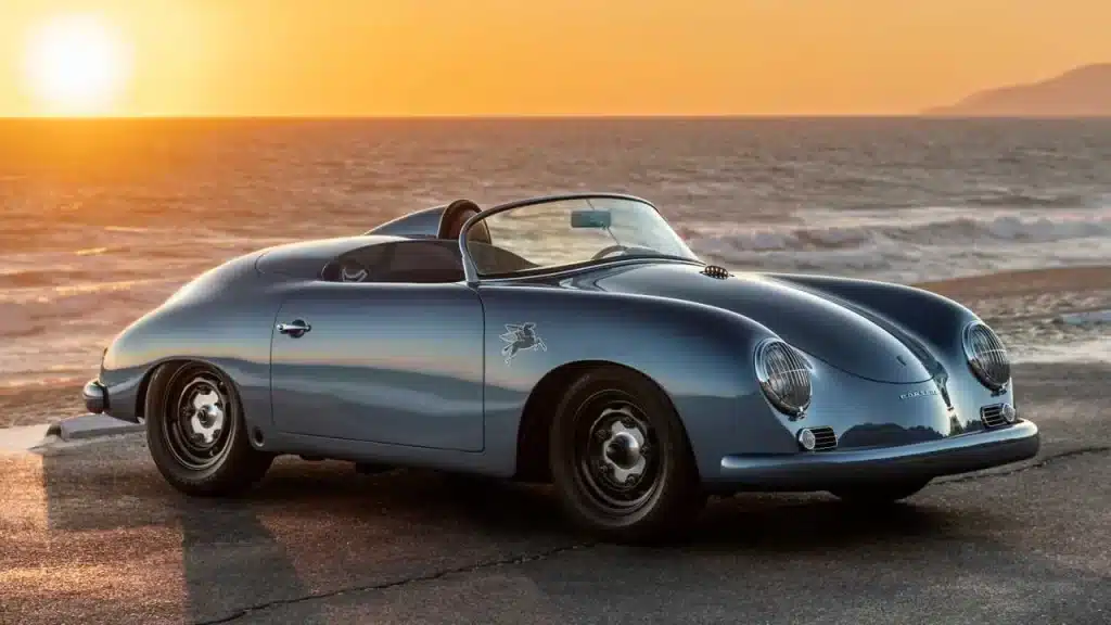 Porsche 356 Speedster is pictured with the sun setting in the background at the beach.