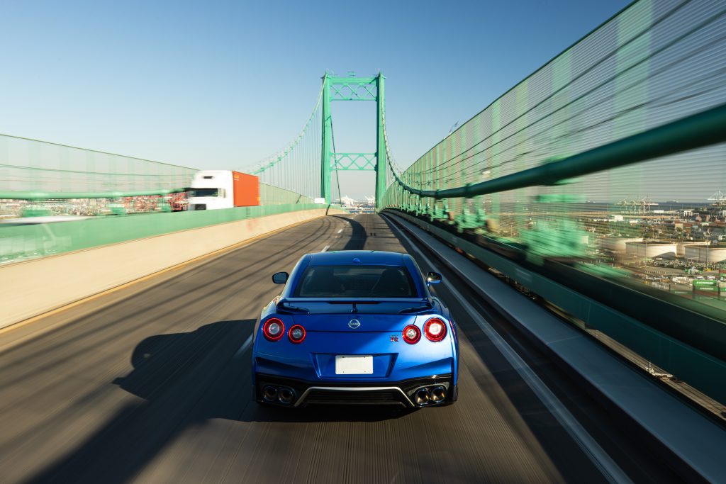 A photo of a Nissan GT-R driving on a bridge.
