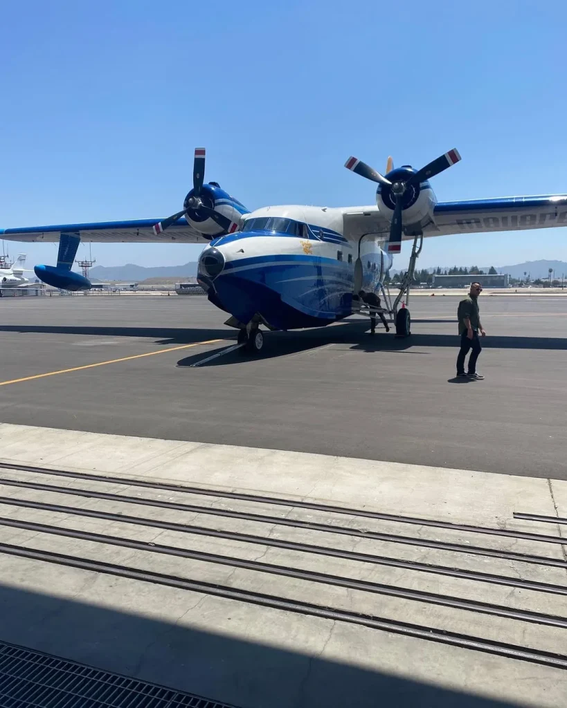 Jay Leno pops out of nose of Grumman HU-16 Albatross airplane flying over the Pacific Ocean