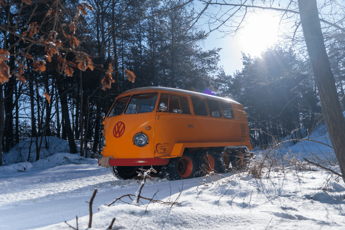 VW kombi campervan transformed into tank with tracks and rolls over snow.