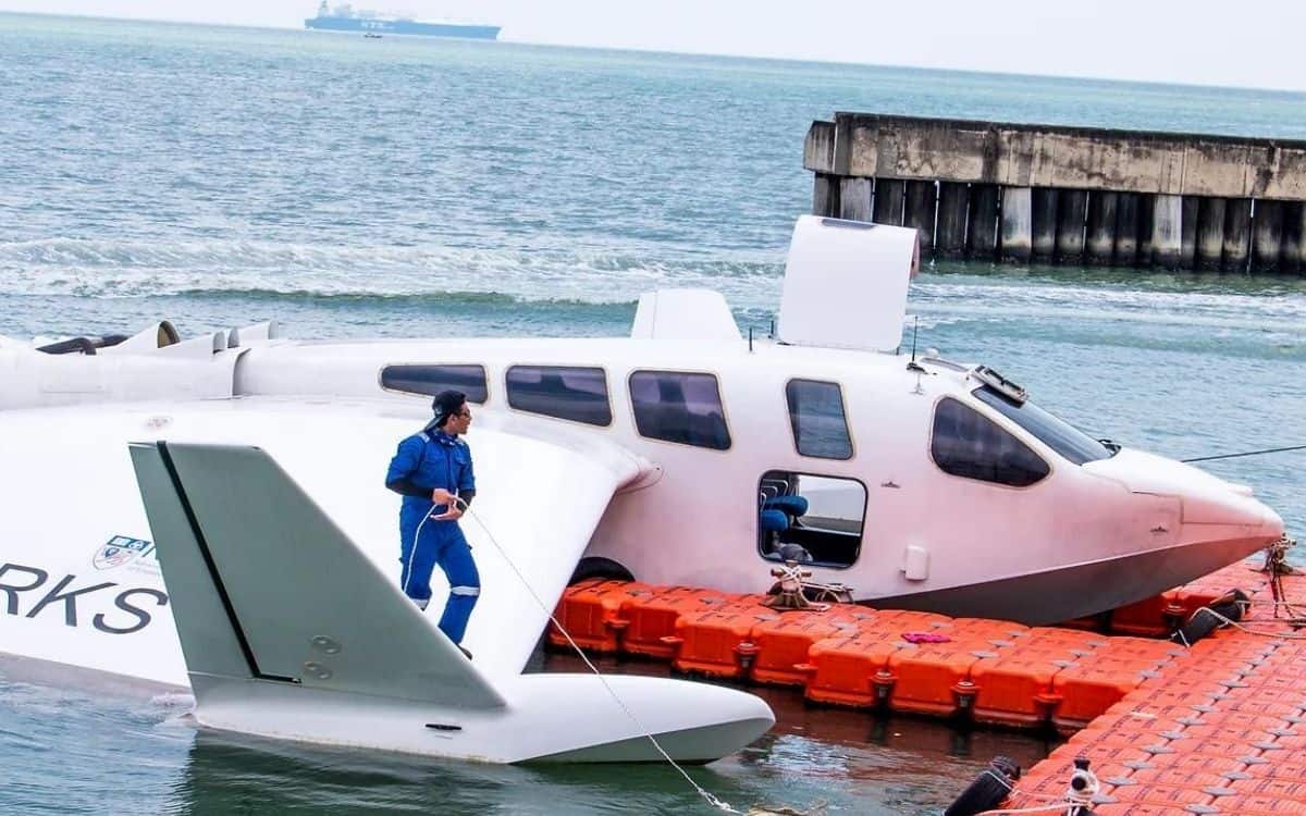 A man stands on the wing of a landed Airfish 8 boat.