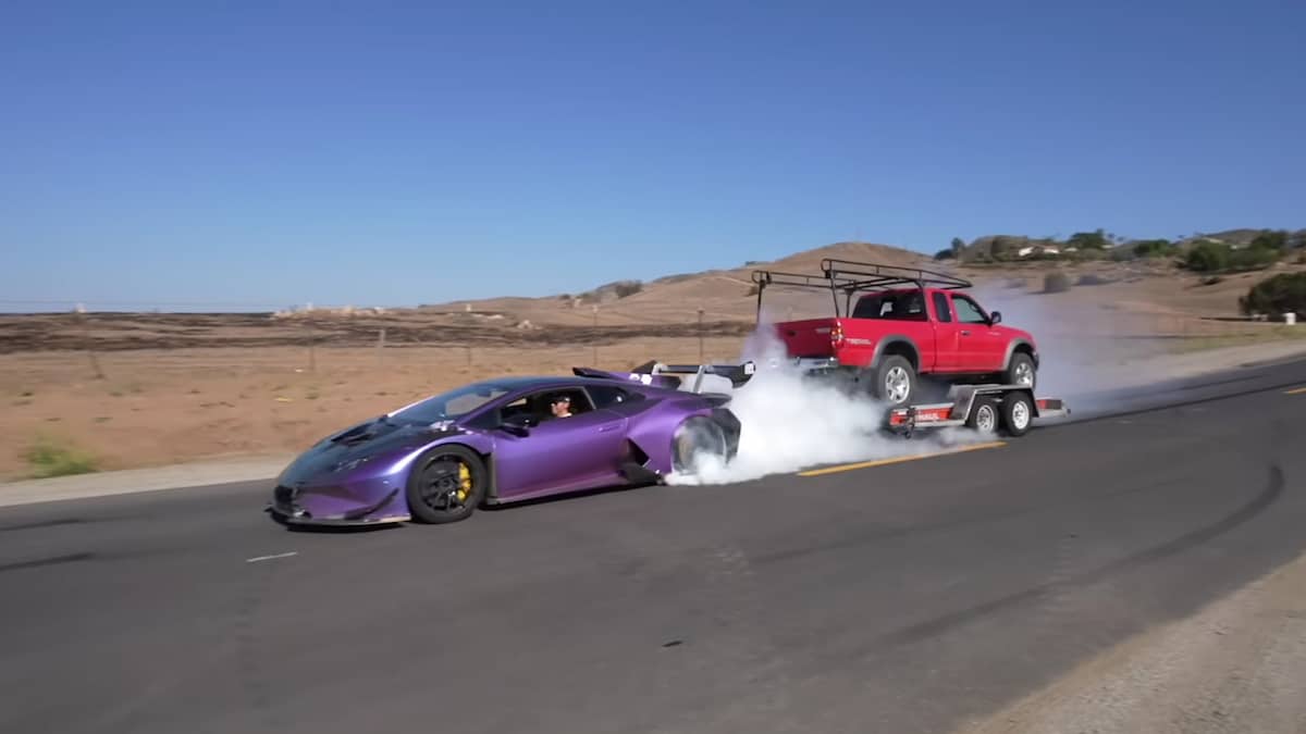 Modified Lamborghini Huracan towing a pickup truck and doing a burnout