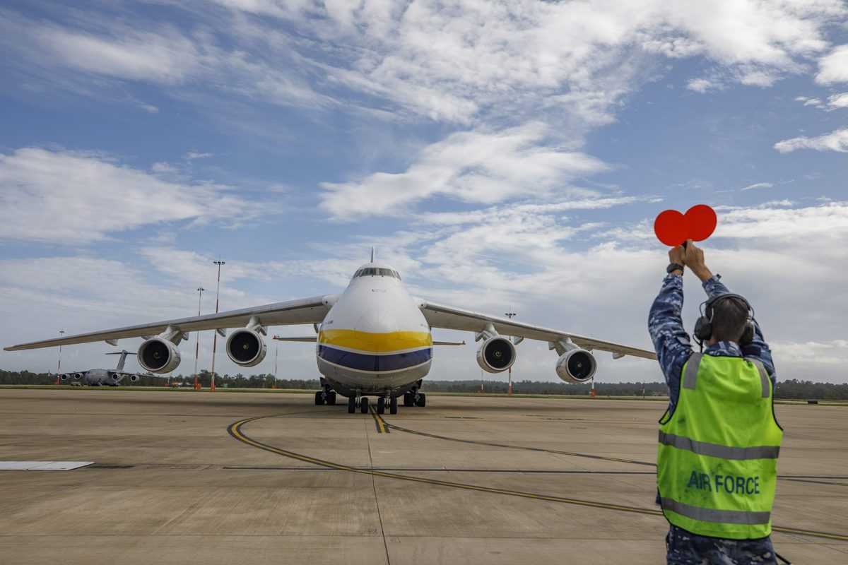 A Royal Australian Air Force air movements operator from No. 23 Squadron marshals an Antonov AN-124 cargo aircraft after it landed at RAAF Base Amberley in Queensland.
