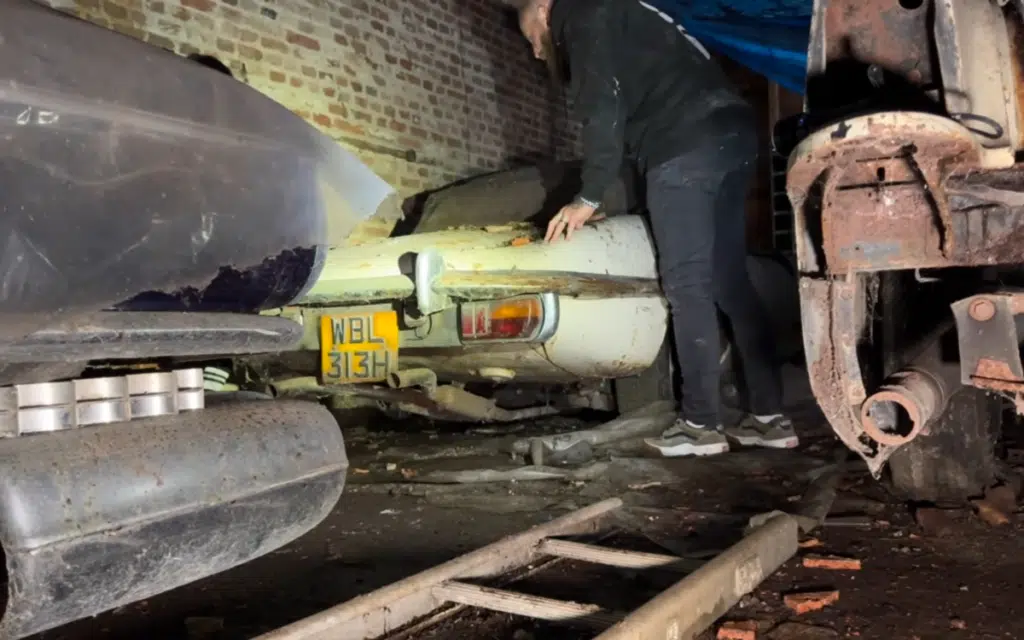 Jaguar E-Type next to American car, the Cadillac Fleetwood, in amazing barn find