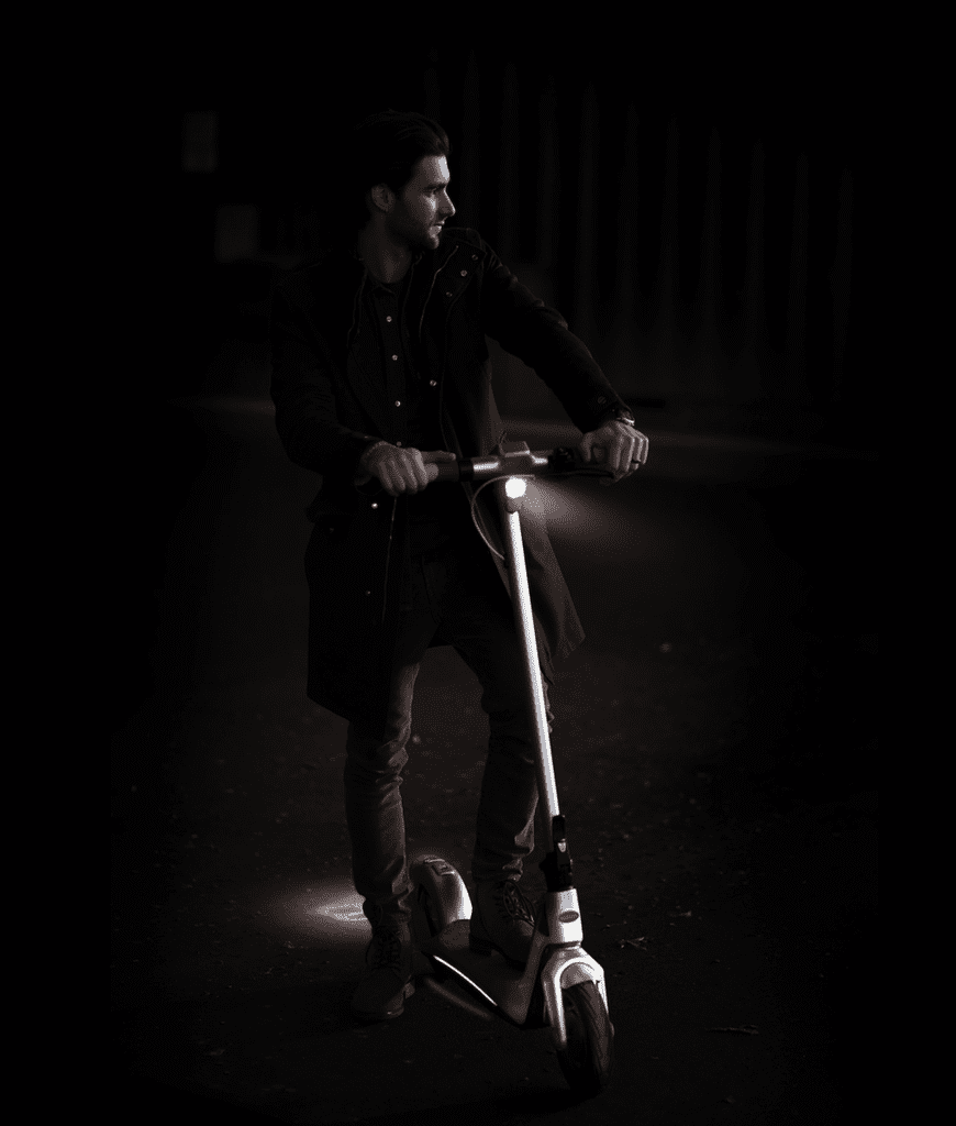 A man rides the Bugatti scooter in the dark.
