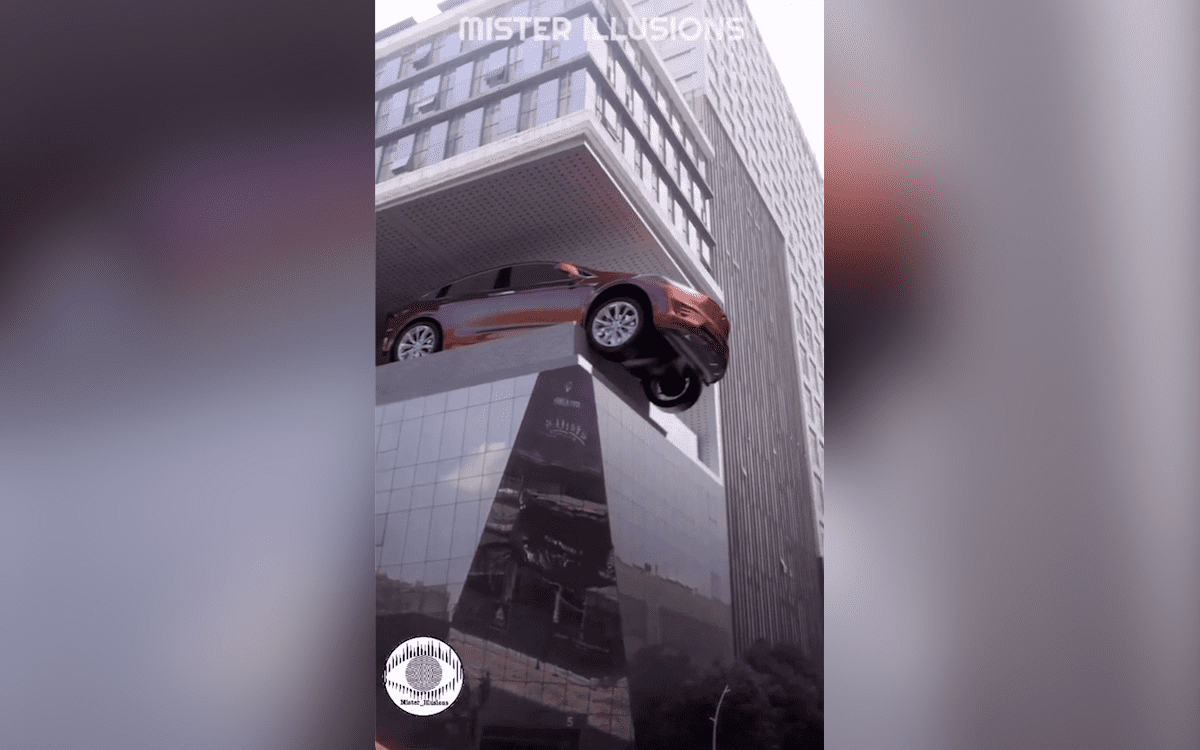 A billboard ad for a car gives the optical illusion its driving off a building.