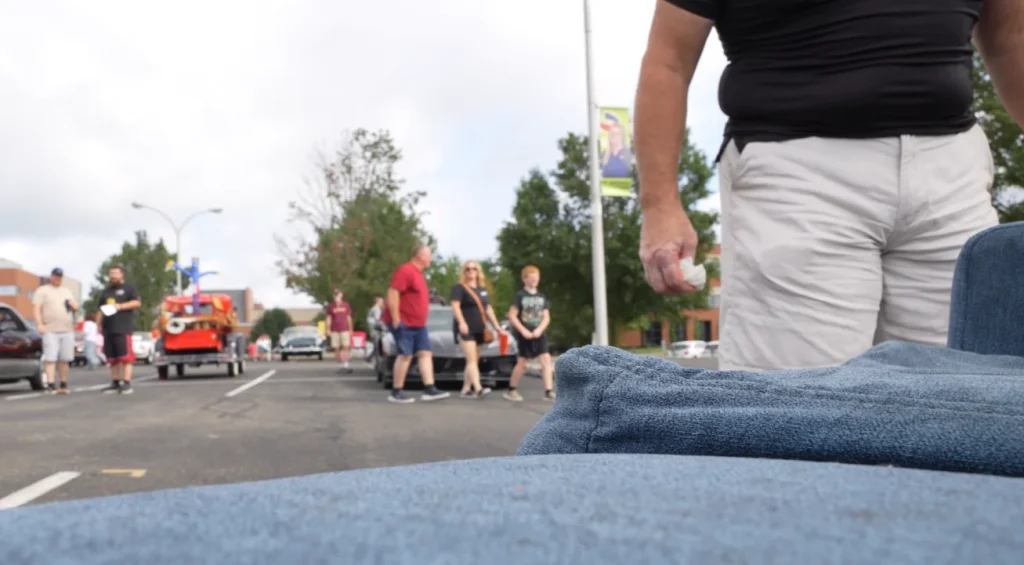 Man crashes a car meet by driving a fully functional, motorized living room couch and immediately upsets a Porsche owner
