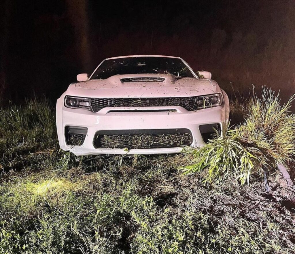 Dodge Charger in a swamp, front end damage and debris