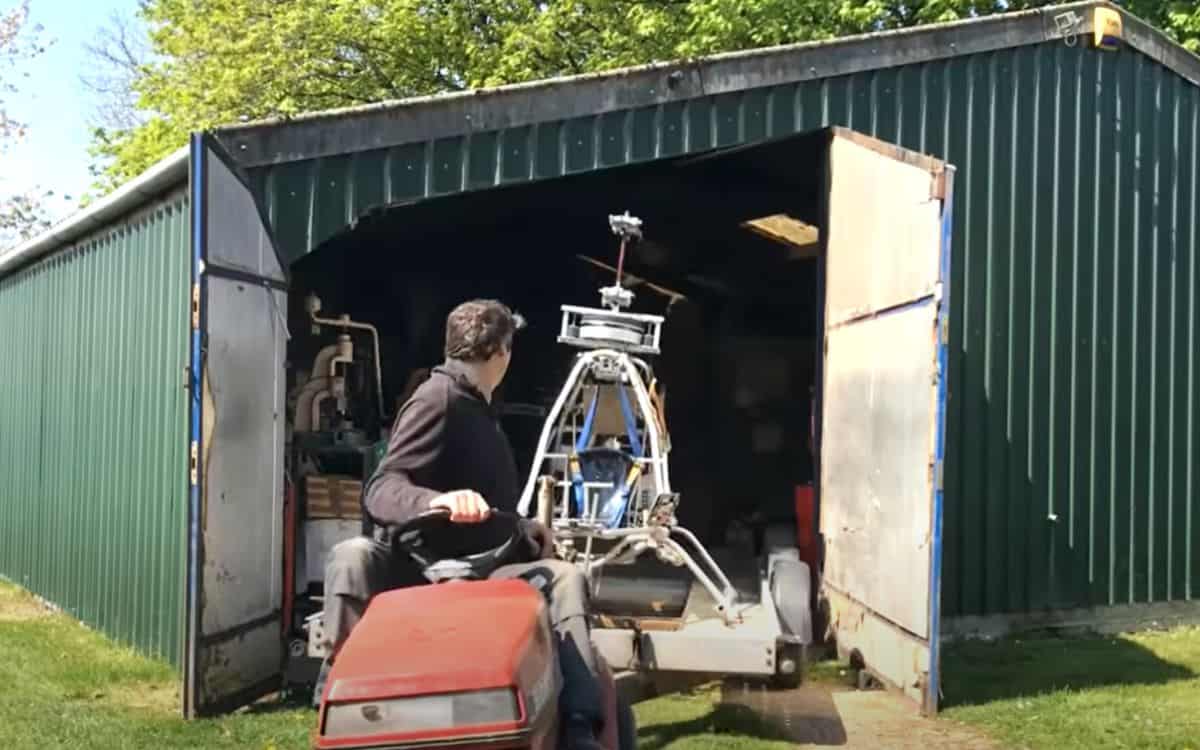 The homemade helicopter is towed out of a shed with a ride-on lawnmower.