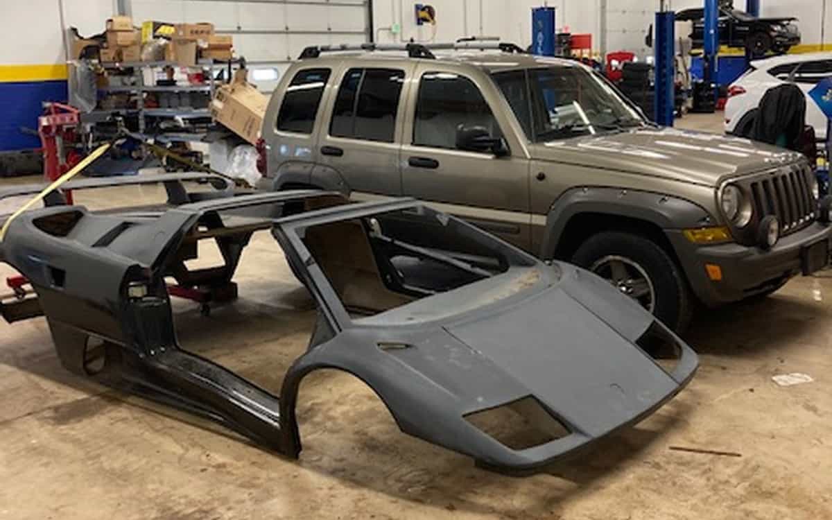 A Jeep Liberty pictured with the frame of a Lamborghini Diablo.