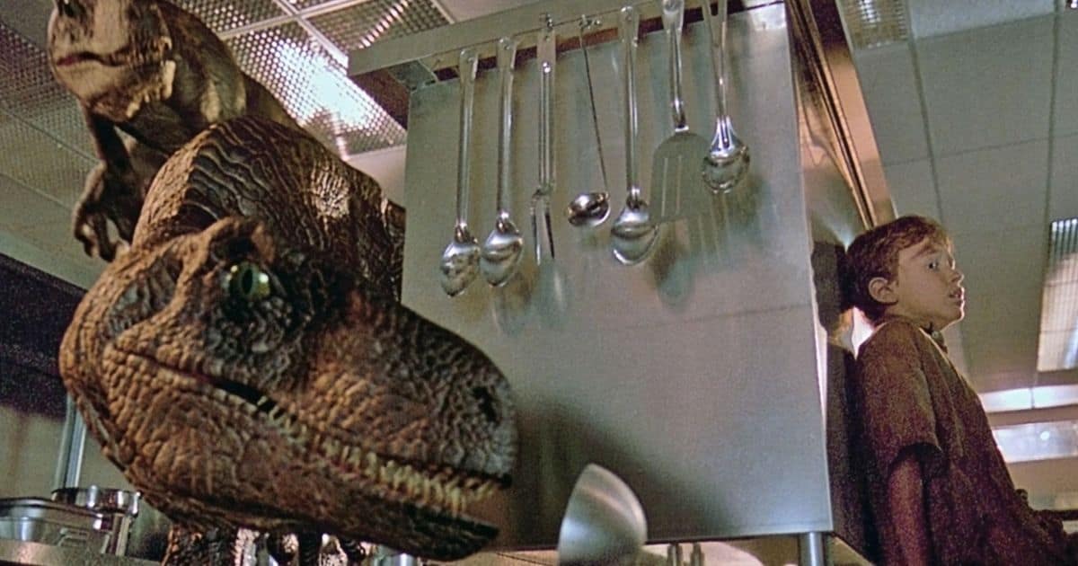 Velociraptors stalk children in kitchen during Jurassic Park.