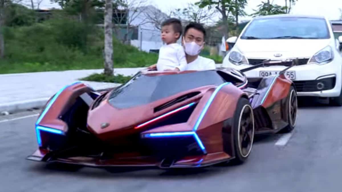 A man and child sit inside a wooden Lamborghini Vision GT.