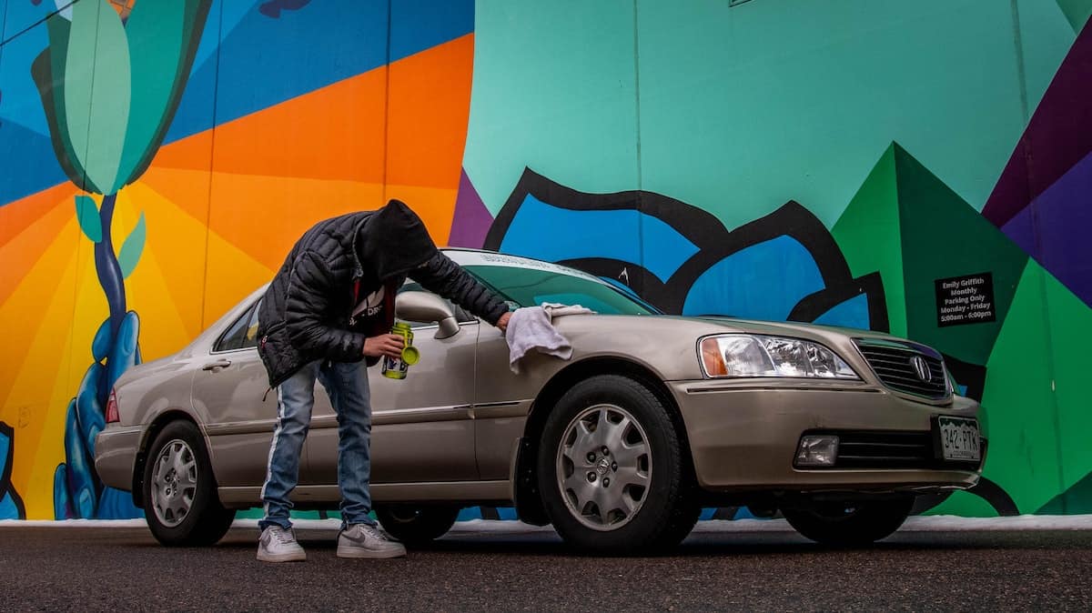 A person applying polish to an Acura car with cloth.
