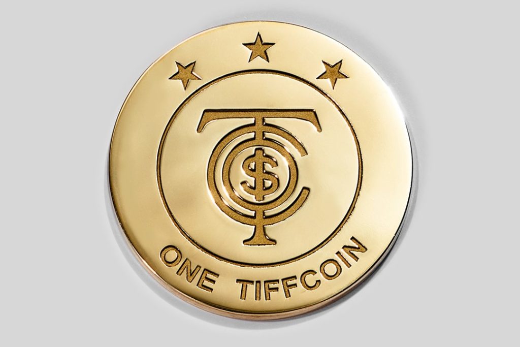 A gold coin with the words "one TiffCoin" engraved on it.