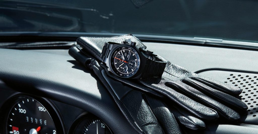 The reissued Chronograph 1 by Porsche Design sits on a pair of black gloves.