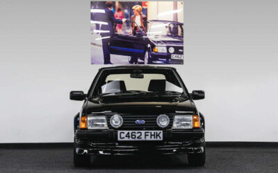 Ford Escort RS Turbo parked in front of image of Princess Diana getting out of the same car
