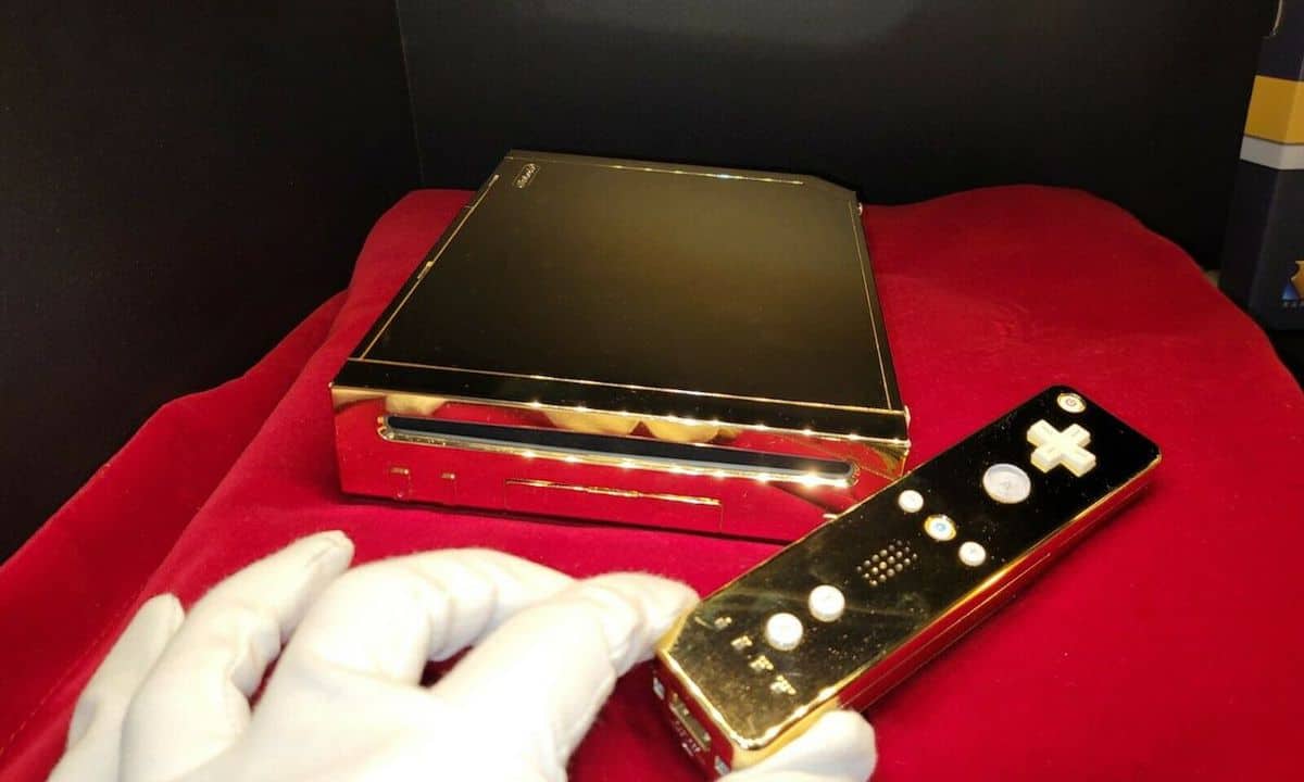 A gloved hand handles the golden Wii owned by Queen Elizabeth.