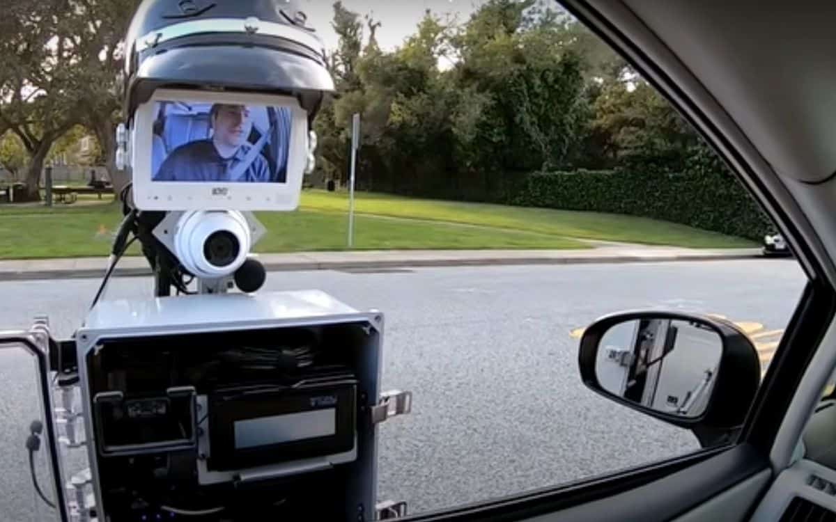 A screen shows a man in a car on the robot cop.