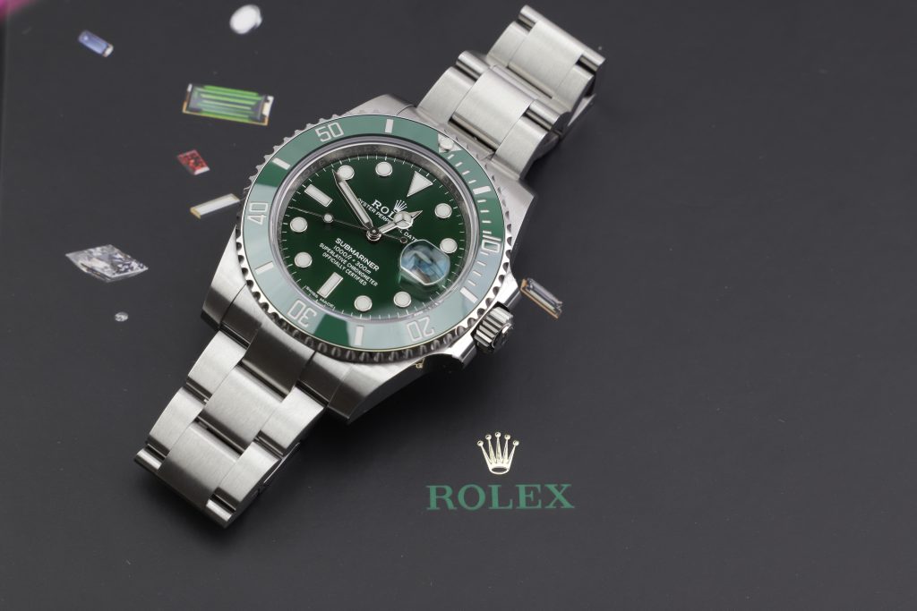 Rolex 'Hulk' laying next to the brand's logo.