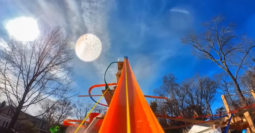 Someone built a 12-foot-tall Hot Wheels track that starts on a roof and uses water, lifts, and buckets to keep a tiny car moving through an entire backyard