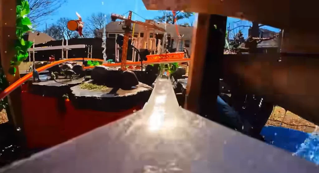 Someone built a 12-foot-tall Hot Wheels track that starts on a roof and uses water, lifts, and buckets to keep a tiny car moving through an entire backyard