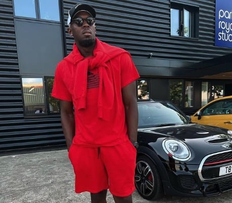Usain Bolt loses millions - pictured posing with a car