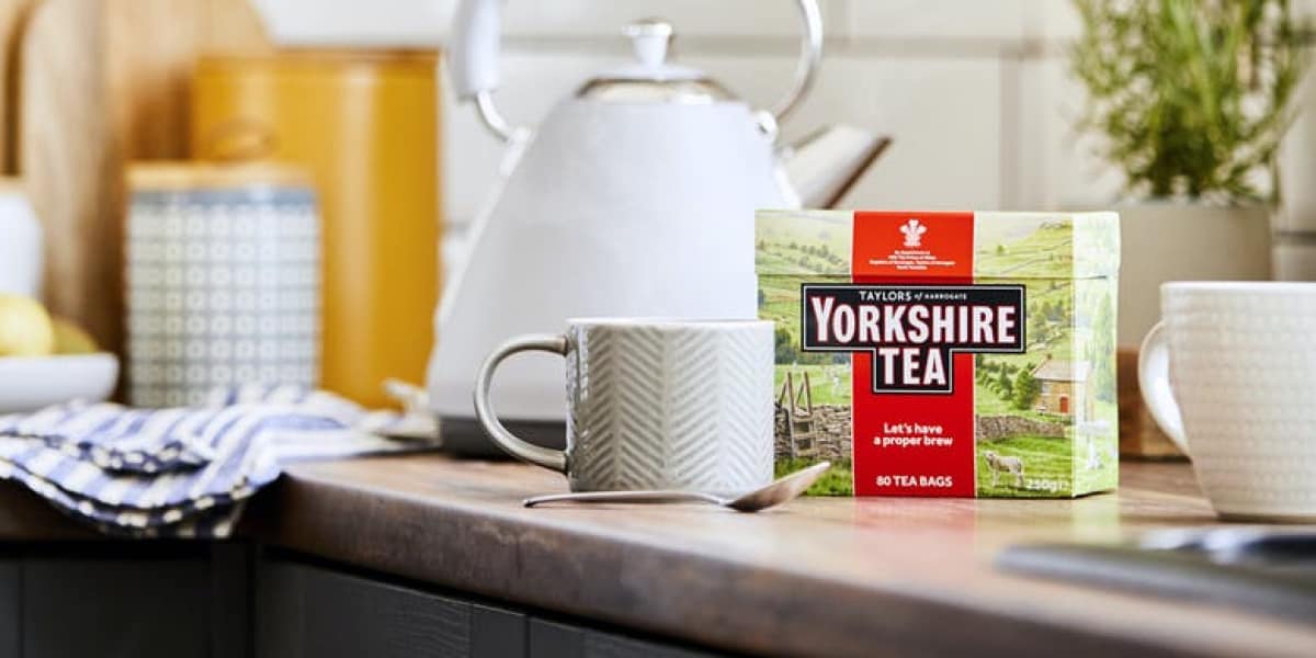Yorkshire Tea next to a kettle and mug on a kitchen bench.