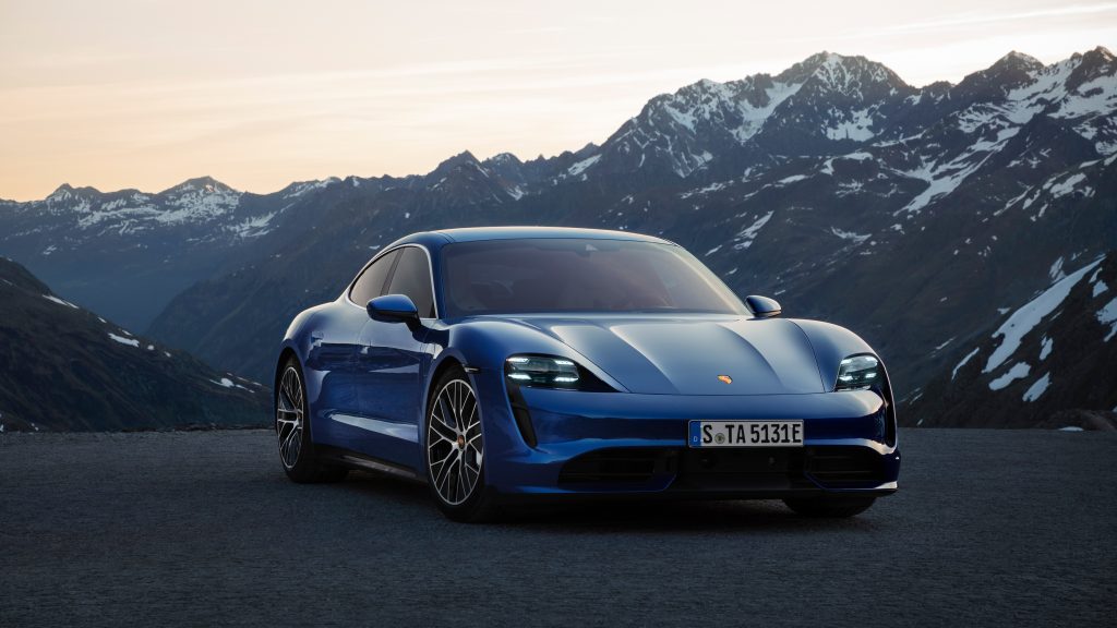 The front of a blue Porsche Taycan Turbo S with mountains in the background.