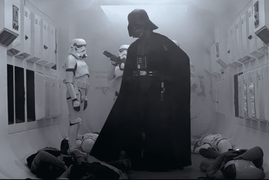 A still of Darth Vader with stormtroopers in the background.