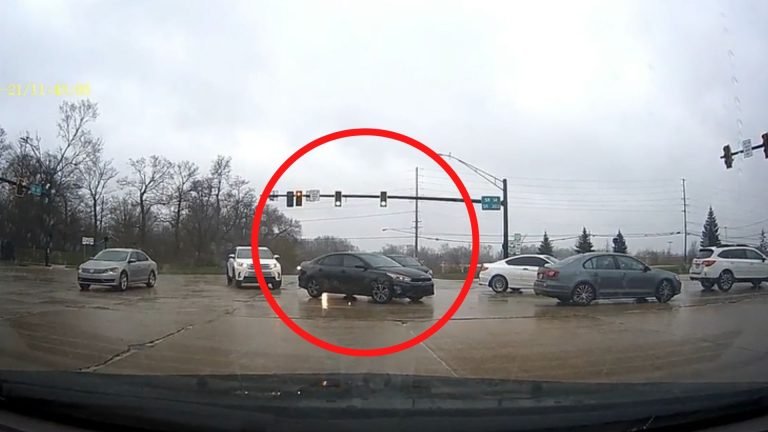 A line of cars at an intersection shown in dashcam footage.