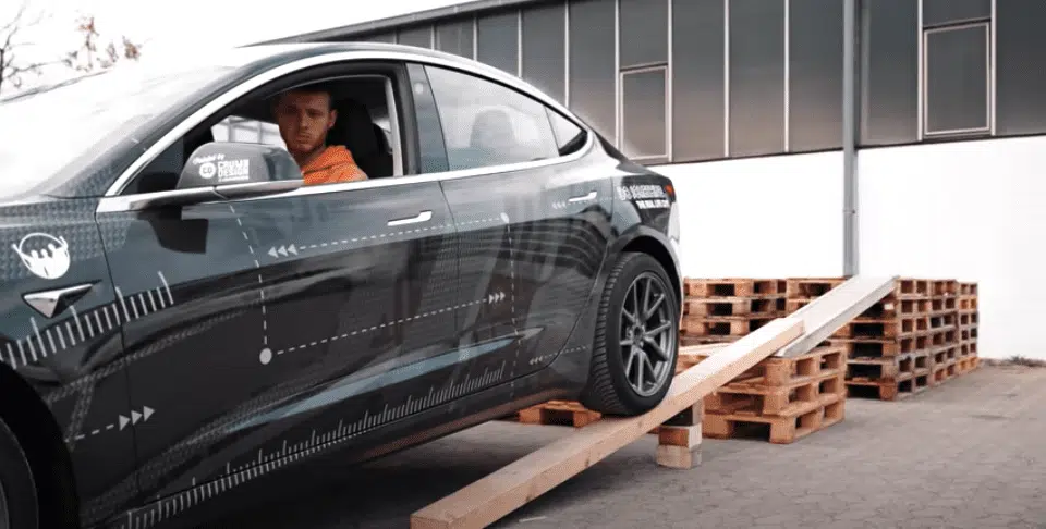 A man backing up the Tesla onto wooden pallets.